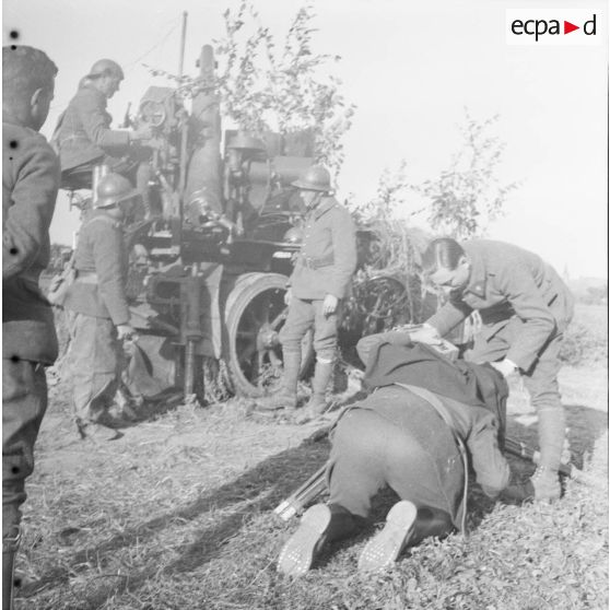 [Une équipe de tournage filme les servants d'un canon camouflé de 75 mm CA autocanon M1913/1934 du 402e RADCA (régiment d'artillerie de défense contre avions). Gavisse (Moselle), 18-22 octobre 1940.]