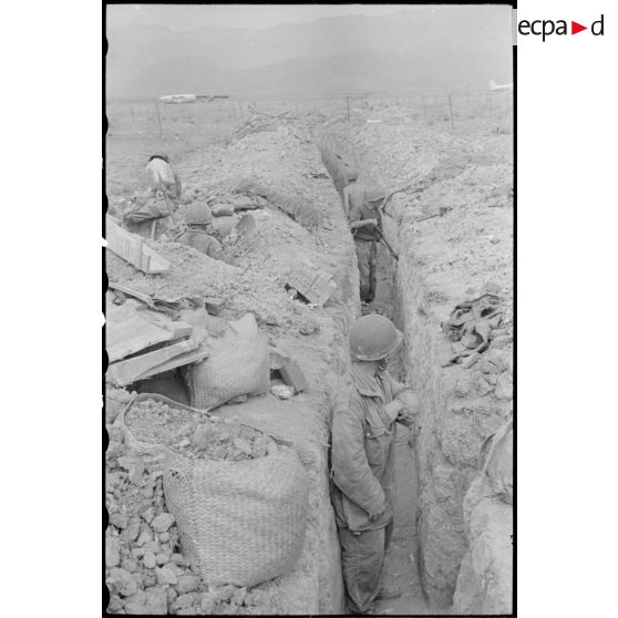 Aux abords immédiats de la piste d'atterrissage du camp retranché de Diên Biên Phu, des parachutistes renforcent les positions de défense.