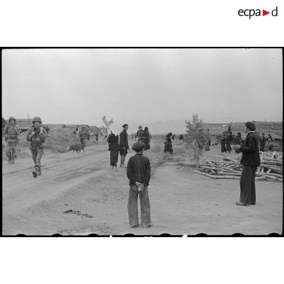 Des troupes parachutées près du camp de Diên Biên Phu traversent un village habité par des Thaï.