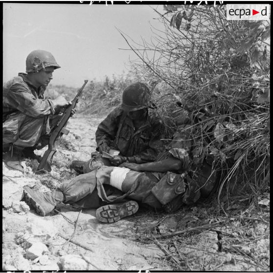 Un soldat blessé est soigné à l'abri des hautes herbes, lors d'une contre-attaque menée sur les positions Viêt-minh au sud de Diên Biên Phu.