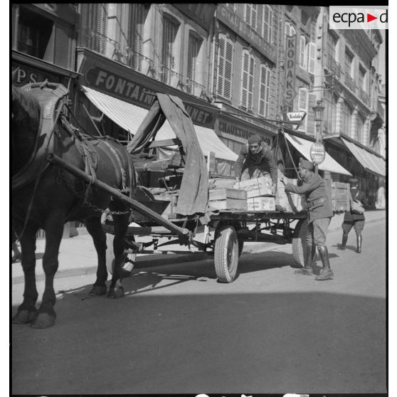 Plan général de soldats français qui chargent une charrette dans une rue.