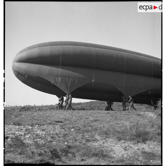 Des aérostiers maintiennent au sol un ballon de protection.