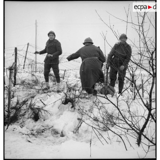 Trois soldats de la 2e armée sont photographiés alors qu'ils marchent dans un paysage enneigé.