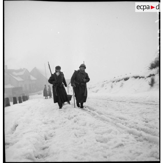 Deux soldats de la 2e armée tirent un traîneau sur la neige.