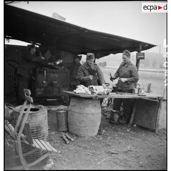 En plein air des cuisiniers de la 2e armée préparent à manger sur une cuisine roulante du cantonnement.