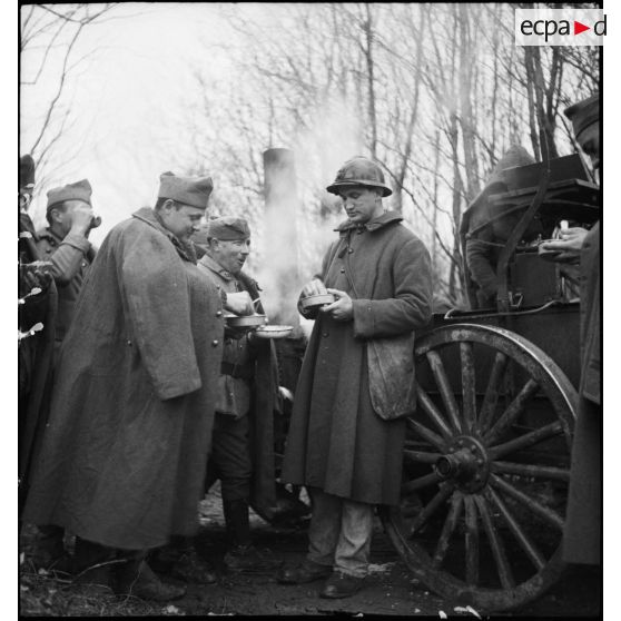 Photographie de groupe de soldats de la 2e armée qui mangent debout près d'une cuisine roulante.