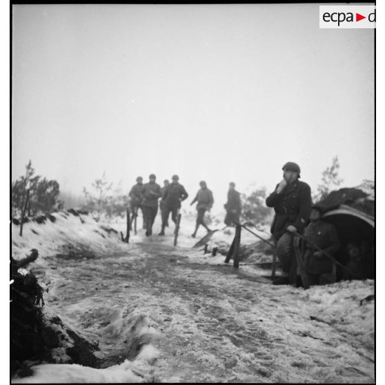 Plan général d'artilleurs du 402e RAAA qui courent dans la neige à l'appel d'un officier.