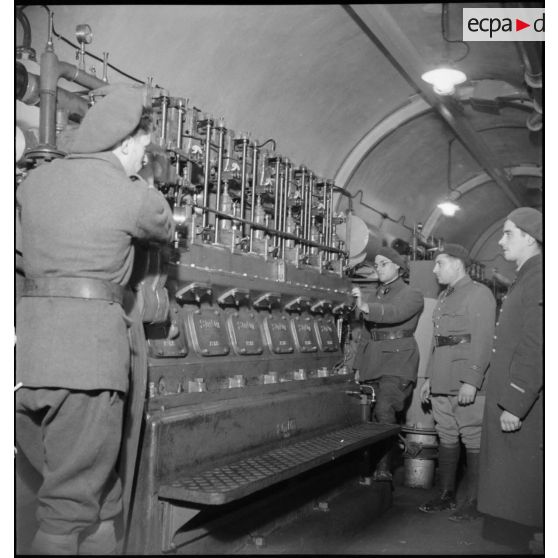 Deux officiers, dont un lieutenant, inspectent l'un des moteurs SMIM de 90 ch qui équipent l'ouvrage de Velosnes.