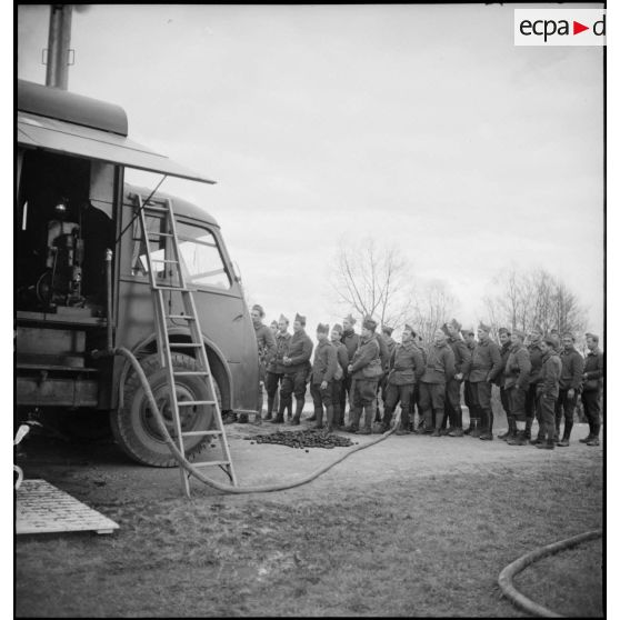 Plan général de soldats de la 2e armée qui regardent l'installation du camion-douche de la SHLD.