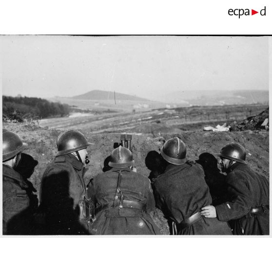 Derrière un talus de terre des soldats de la 4e armée observent le terrain à la binoculaire.