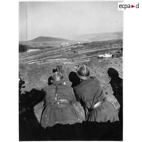 Derrière un talus de terre des soldats de la 4e armée observent le terrain à la binoculaire.