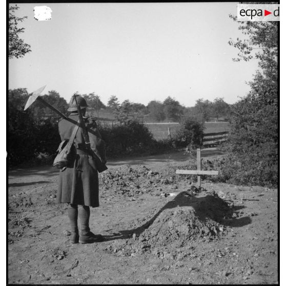 Un soldat de la 4e armée se tient debout devant une tombe.