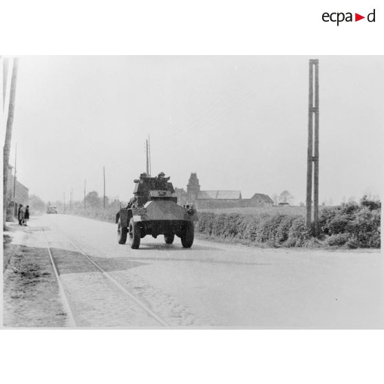 Plan général de face d'une automitrailleuse Guy Mk I du 12e lanciers britannique qui roule sur une route près de Thisnes le 10 mai 1940 à 14 heures.