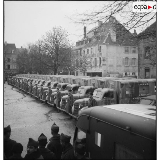 Plan général d'ambulances Chevrolet de la SSVA n°2 (section sanitaire de volontaires américains) rassemblées sur la place d'une ville.