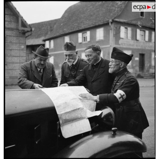 Photographie de groupe d'aumôniers militaires de confessions différentes qui regardent une carte étalée.