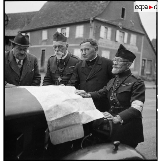 Photographie de groupe d'aumôniers militaires de confessions différentes qui regardent une carte étalée.