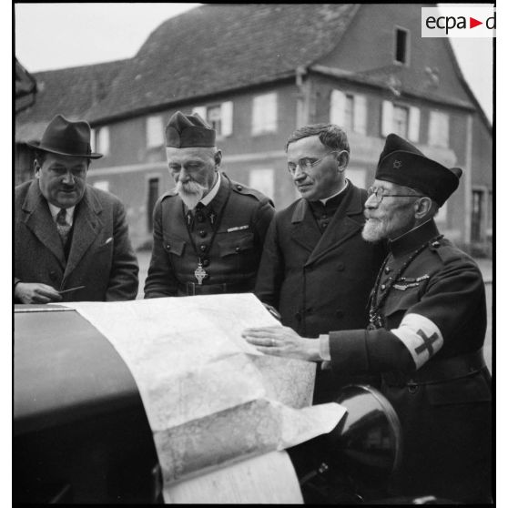 Photographie de groupe d'aumôniers militaires de confessions différentes qui regardent une carte étalée.