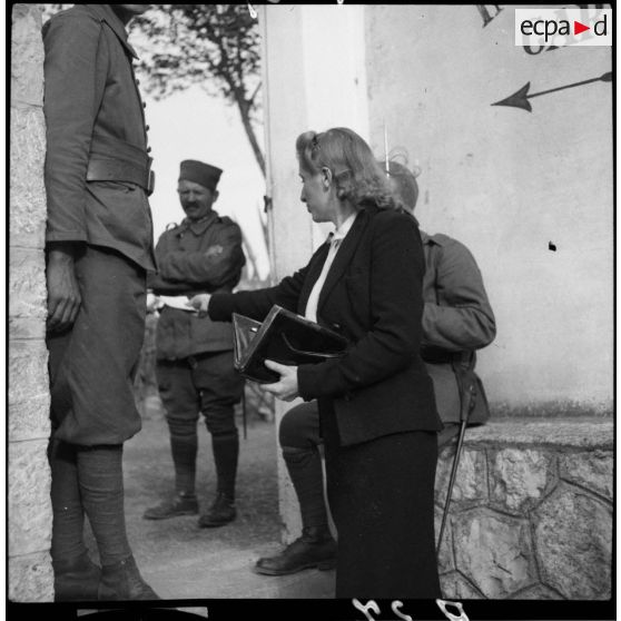 Une femme discute à l'entrée du stade d'Antibes avec des tirailleurs de la 6e armée.