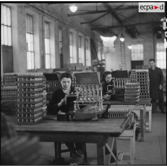 Dans un atelier de l'usine de Valence, une ouvrière travaille sur ce qui semble être des amorces d'obus.