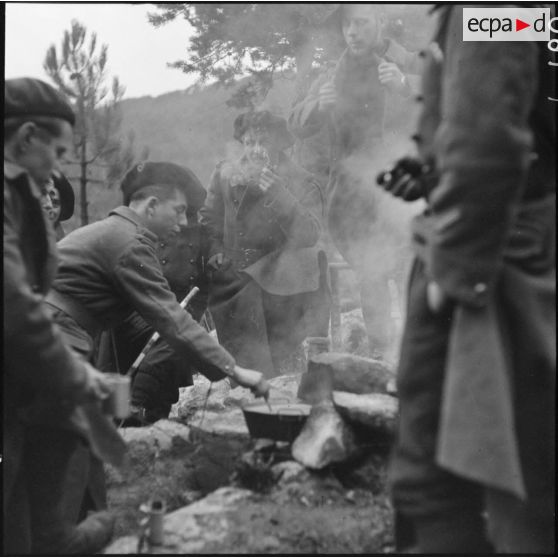 Des chasseurs du 9e BCA sont regroupés autour d'un feu de camp pour faire chauffer un café.