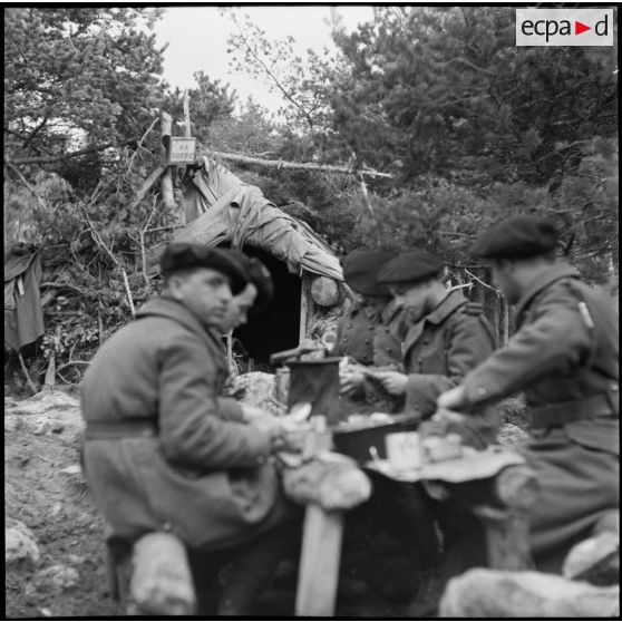 Des chasseurs du 9e BCA mangent autour d'une table en rondin.