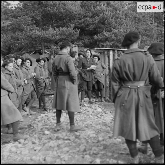 Au campement, des chasseurs du 9e BCA entourent un sergent qui lit un texte.