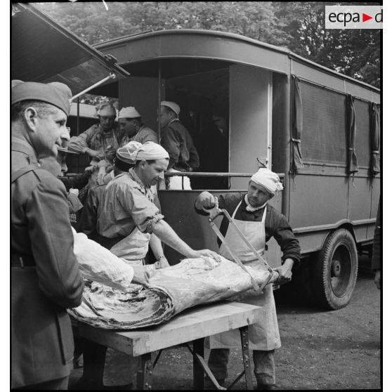 Soldats découpant une importante pièce de viande.