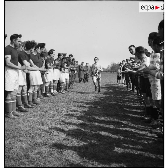 Soldat terminant une course d'athlétisme et félicité par ses pairs.