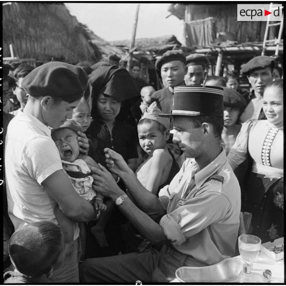 Vaccination d'un bébé Thaï en pleurs par un médecin-capitaine du Service de santé dans un village de la vallée de Diên Bien Phu.