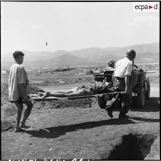 Depuis le centre de résistance Isabelle, évacuation de blessés à bord d'une jeep sur laquelle les brancards sont  posés. Le photographe du SPI (Service presse information) Jean Péraud a pris le volant.