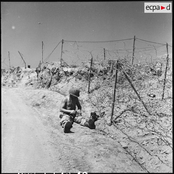 Un monteur de ligne réparant les dégâts causés par l'artillerie Viêt-minh, près du centre de résistance Isabelle du camp retranché de Diên Bien Phu.