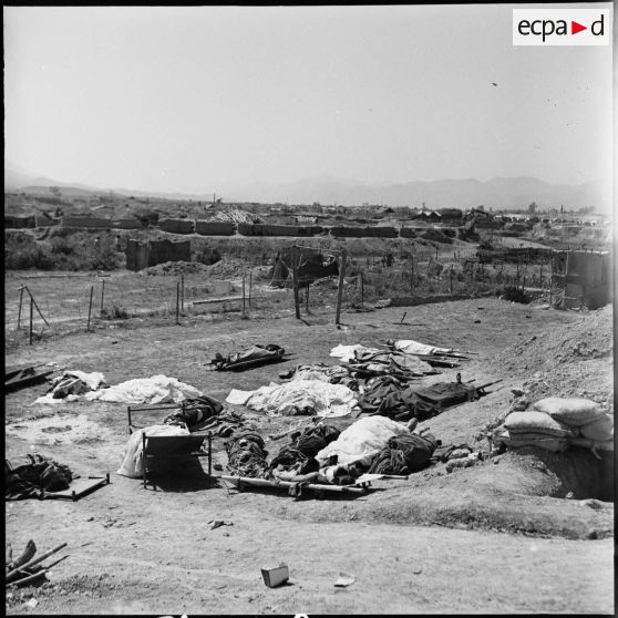 Les corps de soldats morts au combat, emmaillotés ou recouverts d'un tissu, gisent au sol près d'un point d'appui du camp retranché de Diên Biên Phu.