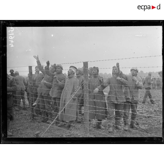 Etinehem (Somme). Camp de prisonniers. Groupe de prisonniers derrière les clôtures, on leur jette du pain. [légende d'origine]