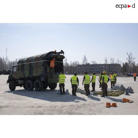 Des logisticiens du 503e régiment du train (503e RT) et des légionnaires du 2e régiment étranger d'infanterie (2e REI) rangent des sangles et des cales à bord d'un camion GBC-180 à Tapa, en Estonie.