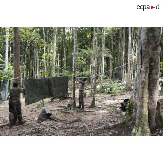 Des stagiaires du régiment du service militaire adapté (RSMA) tendent une bâche pour le montage d'un bivouac lors d'un atelier jungle à Saint-Jean-du-Maroni, en Guyane française.