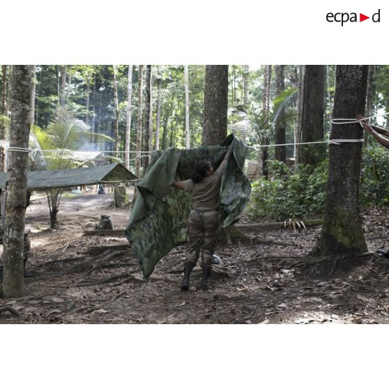 Une stagiaire du régiment du service militaire adapté (RSMA) tend une bâche pour le montage d'un bivouac lors d'un atelier jungle à Saint-Jean-du-Maroni, en Guyane française.