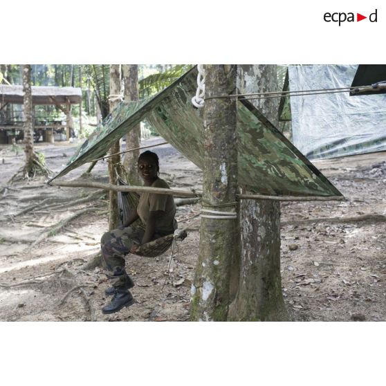 Une stagiaire du régiment du service militaire adapté (RSMA) teste son hamac pour le montage d'un bivouac lors d'un atelier jungle à Saint-Jean-du-Maroni, en Guyane française.