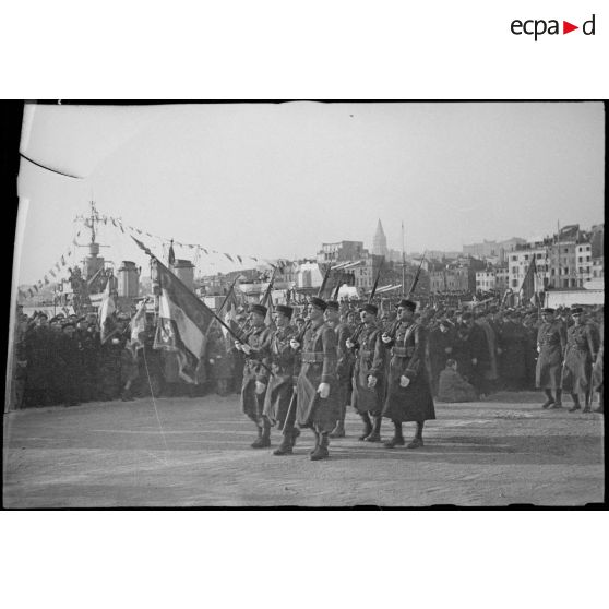 Le drapeau et la garde d'honneur d'un régiment ou d'une école d'élèves officiers défilent sur le quai des Belges du Vieux-Port de Marseille, lors de la visite du maréchal Philippe Pétain.