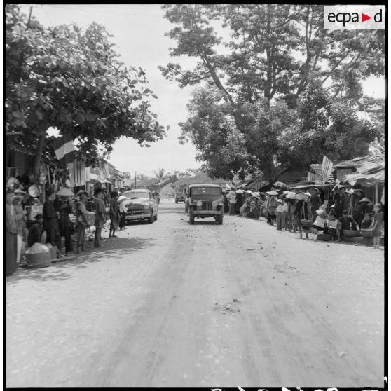 Passage du convoi de véhicules transportant les membres de la mission militaire américaine Melby-Erskine dans les rues pavoisées de Dap Cau.