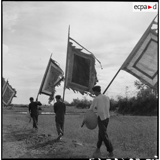 Les drapeaux des génies tutélaires des villages sont promenés le long de la route en l'honneur de la commission américaine Melby-Erskine en visite au Tonkin.