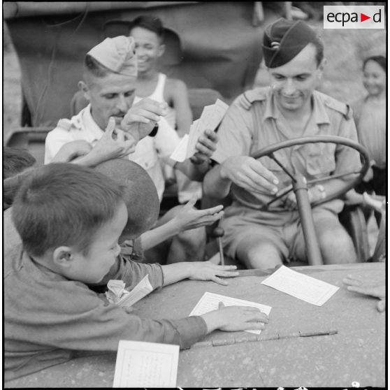 Distribution de documents aux enfants de la communauté catholique de Yen Vi par des militaires se déplaçant à bord d'une jeep.