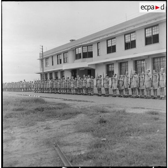 Elèves de l'école des cadres d'Hanoï au présentez-armes devant le bâtiment.