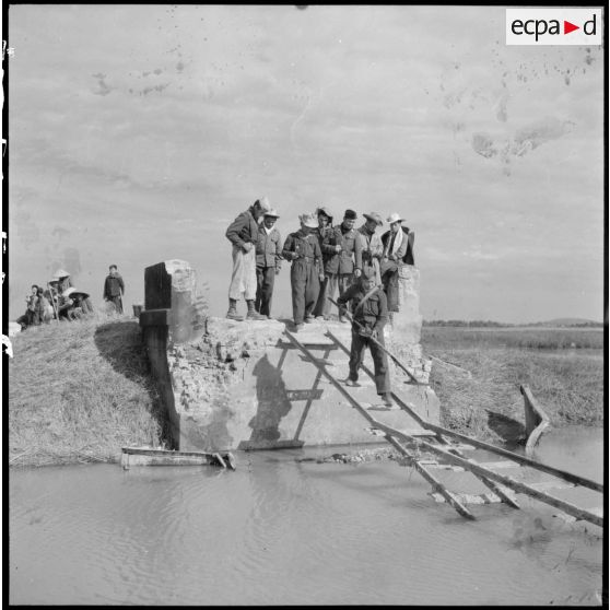 Passage d'un soldat du Génie muni d'un détecteur de mines sur des planches de bois remplaçant un pont détruit sur la route coloniale n°1 au Tonkin.