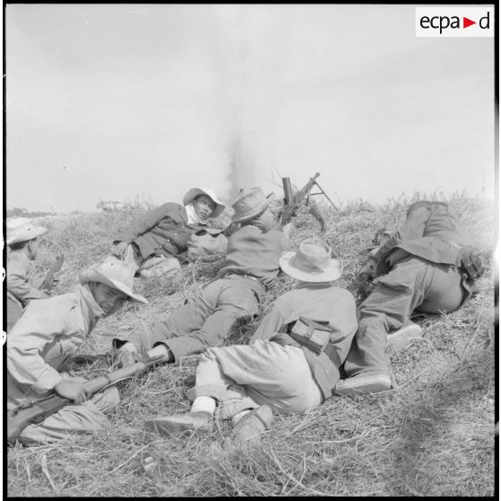 Des soldats vietnamiens armés d'un fusil-mitrailleur FM M24/29 embusqués sur un talus lors d'une attaque.