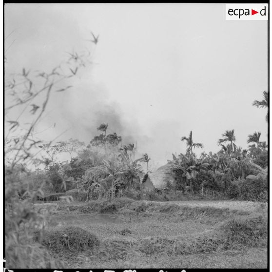 Les hommes du commando trouvent les habitations du village en feu au cours de l'opération Barbe.