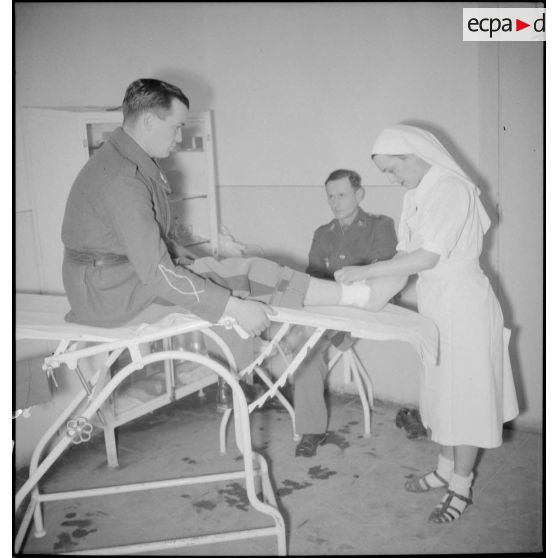 Une infirmière fait un pansement à un élève-officier dans la salle des pansements de l'infirmerie des écoles.