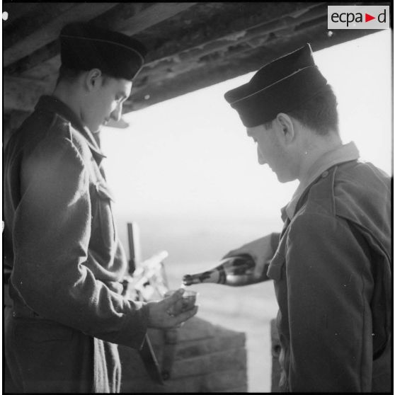 Un soldat sert un verre de champagne à une sentinelle surveillant un poste du delta du Tonkin.