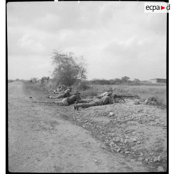 Des légionnaires du 5e REI (régiment étranger d'infanterie) embusqués en position de tir, armés d'une mitrailleuse, au cours d'une opération sur la route entre Hanoï et Haïphong.