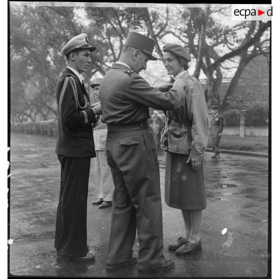 Le général Carpentier, commandant en chef en Indochine, remet la médaille militaire à Geneviève Grall, infirmière du GLAP (Groupement léger aéroporté), au cours d'une prise d'armes à Hanoï.