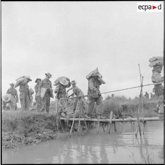 Franchissement d'un arroyo sur un pont de fortune par une compagnie de parachutistes au cours de l'opération Méduse.